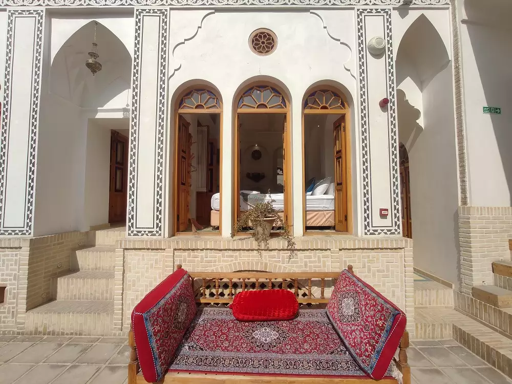 تخت سنتی قرمز در برابر ایوان قوسی هتل صباغیان