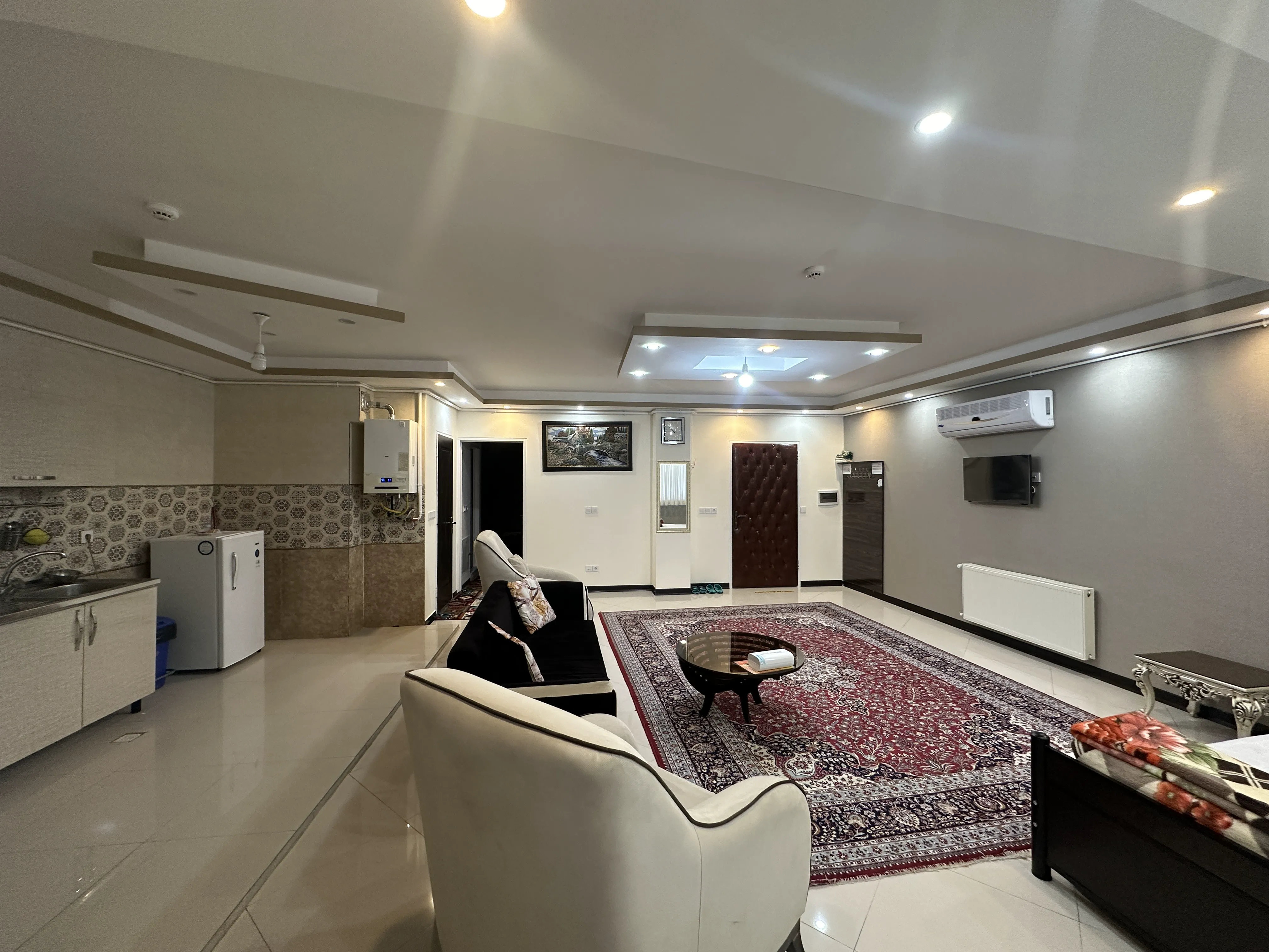 پذیرایی اقامتگاه آرامش با مبل سفید و فرش قرمز