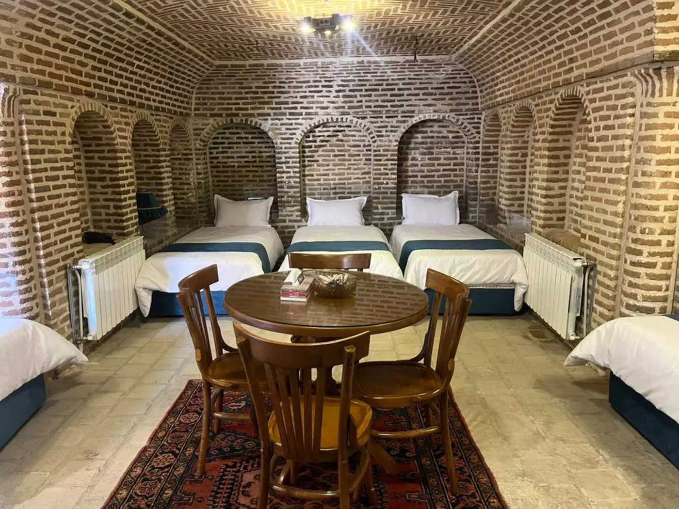 اتاق سه‌تخته هتل ارغوان قزوین با دیوارهای آجری