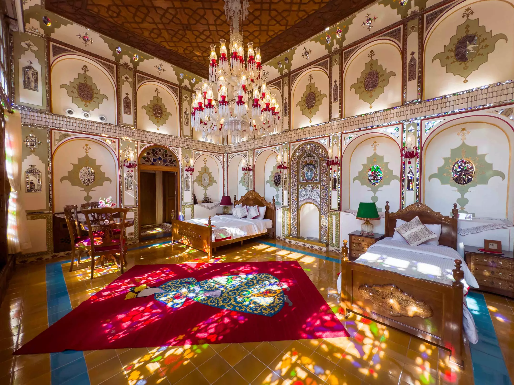 اتاق خواب عمارت شهسواران با لوستر و شیشه‌های رنگی