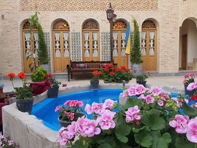 حیاط هتل گل آرا با حوض آبی و گلهای صورتی