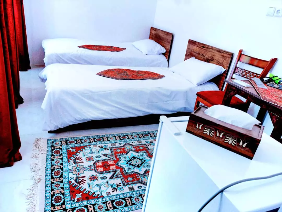 دو تخت یک‌نفره و فرش طرح‌دار در عمارت پدری