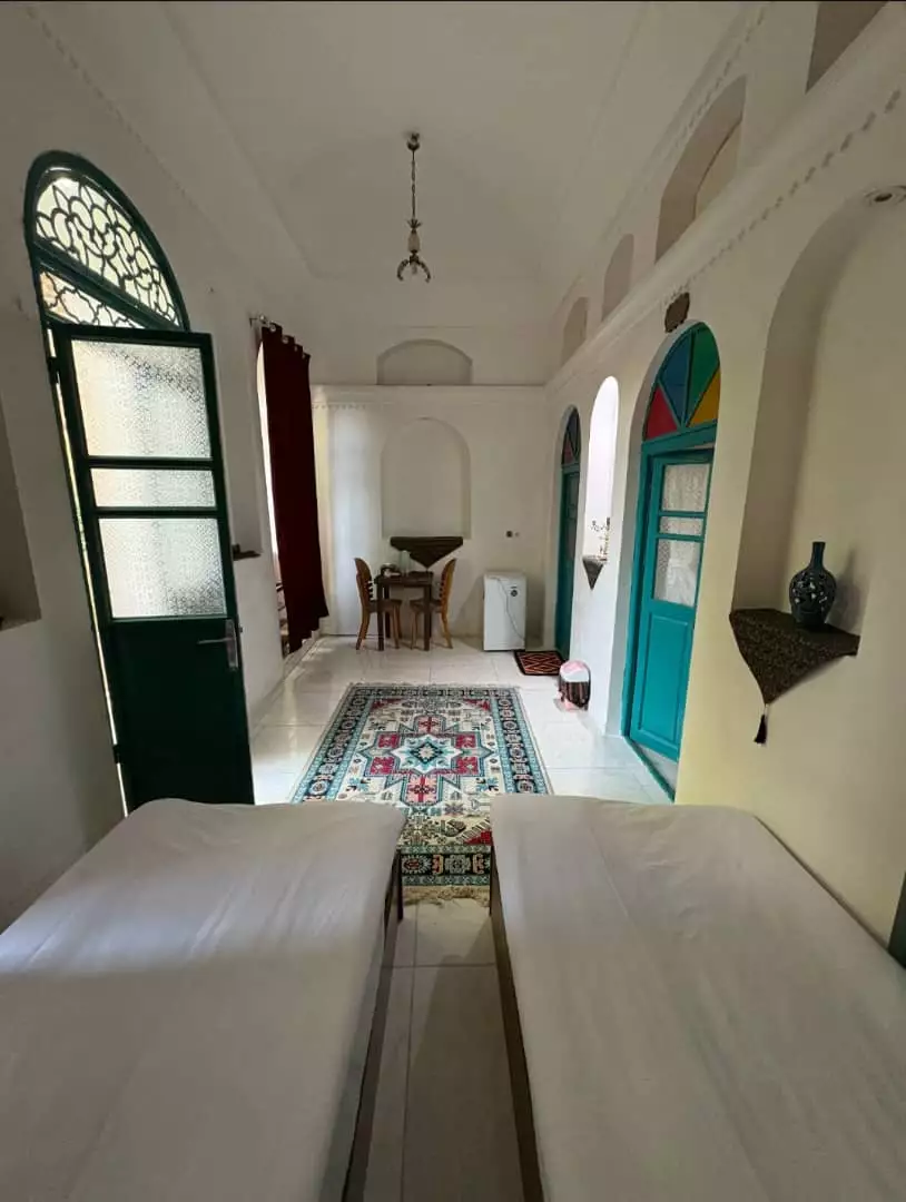 اتاق عمارت پدری با درهای چوبی فیروزه‌ای و فرش سنتی