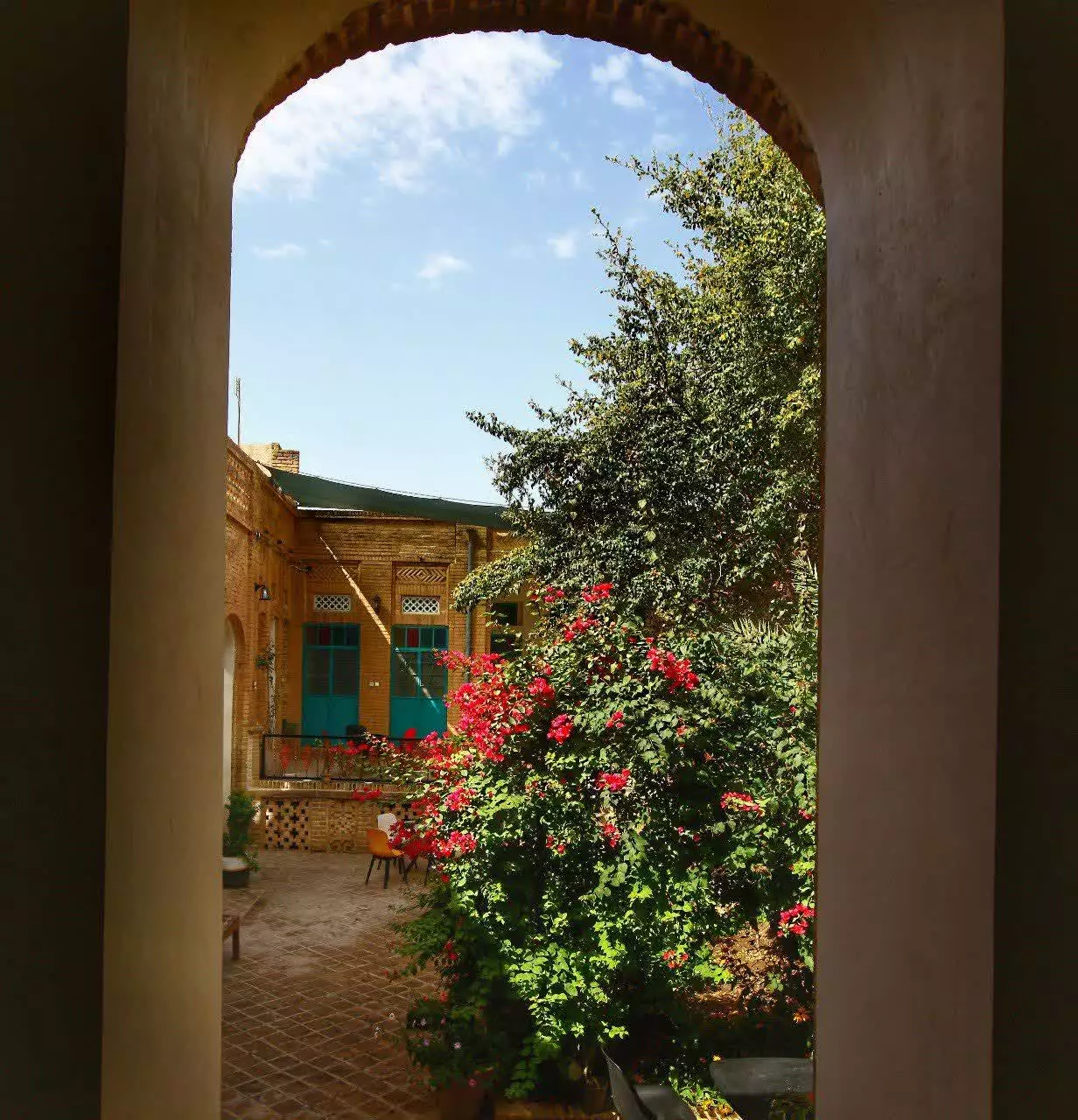 حیاط سرسبز عمارت پدری از قاب ورودی قوسی