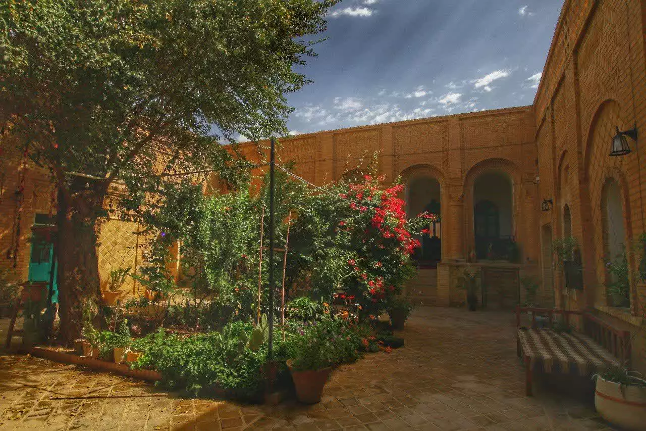 حیاط آجری عمارت پدری با درختان و ایوان قوسی