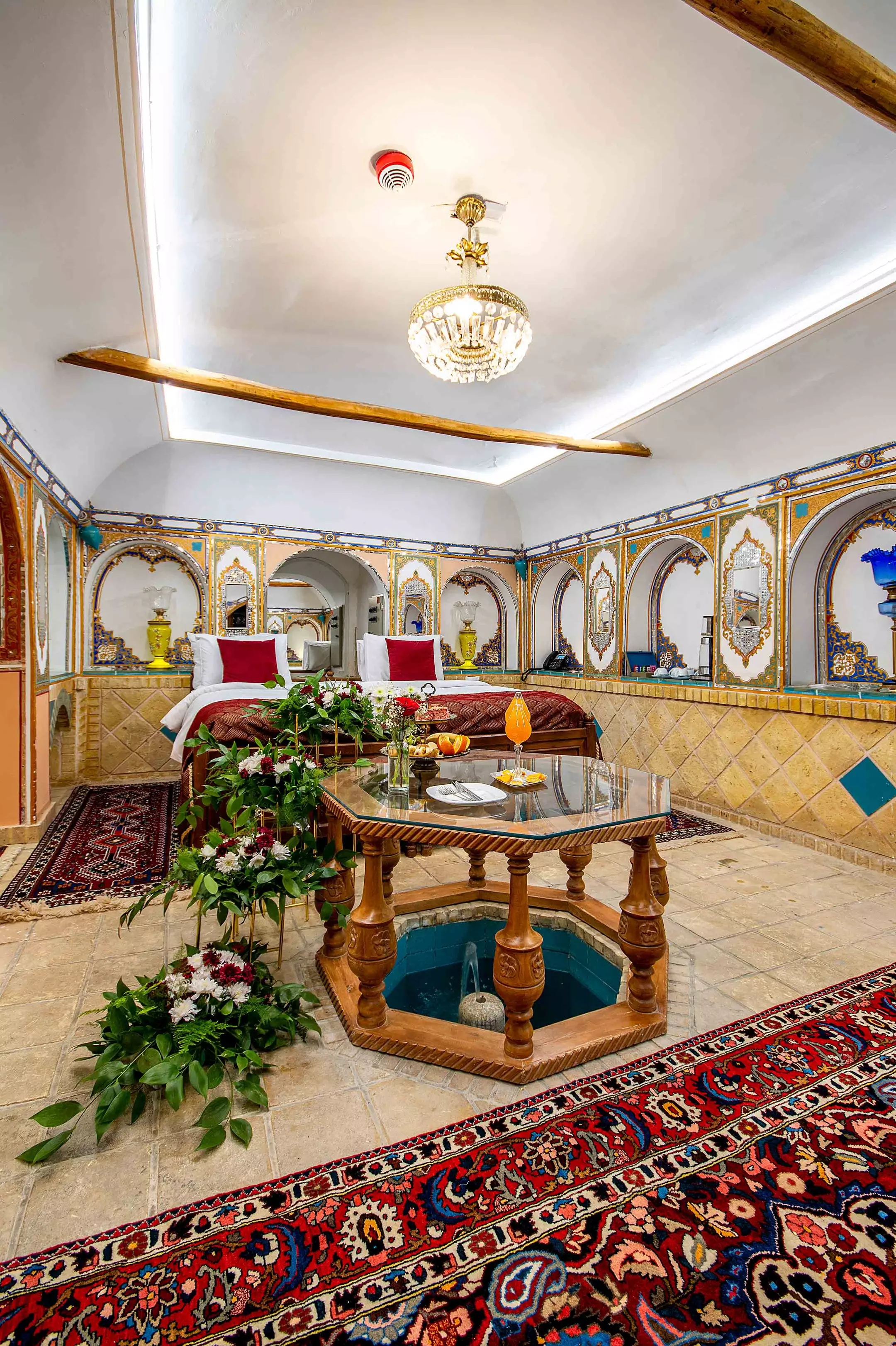 اتاق قصر منشی با تخت، میز هشت‌ضلعی و فرش ایرانی