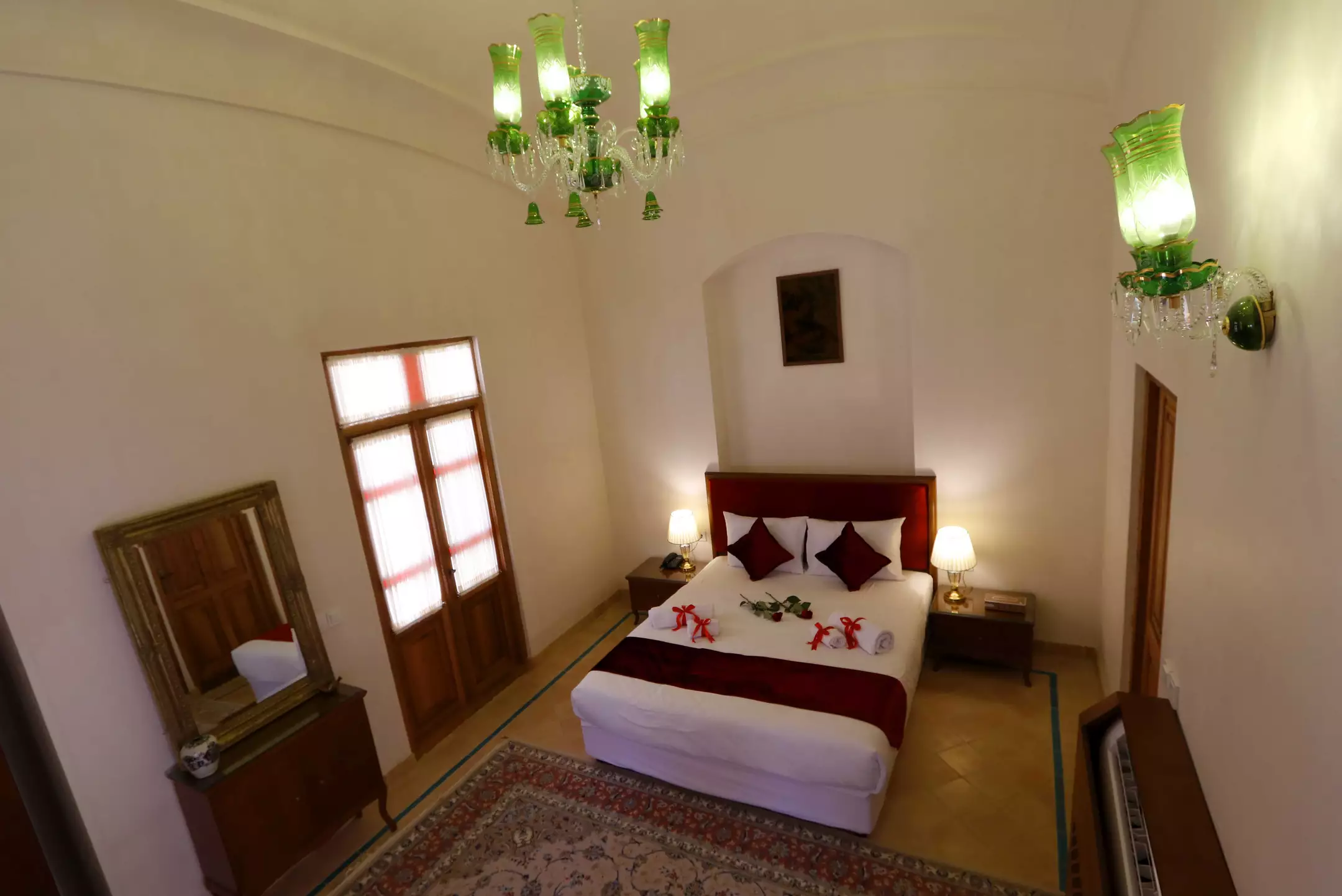 اتاق خواب با تخت دونفره و لوستر سبز در عمارت ماندگار