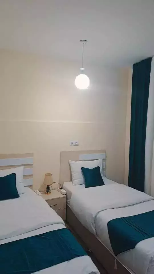 دو تخت یکنفره با روتختی سبزآبی در هتل پدرمن