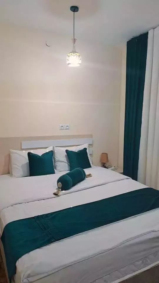 تخت دونفره سفید با روتختی سبزآبی در هتل پدرمن
