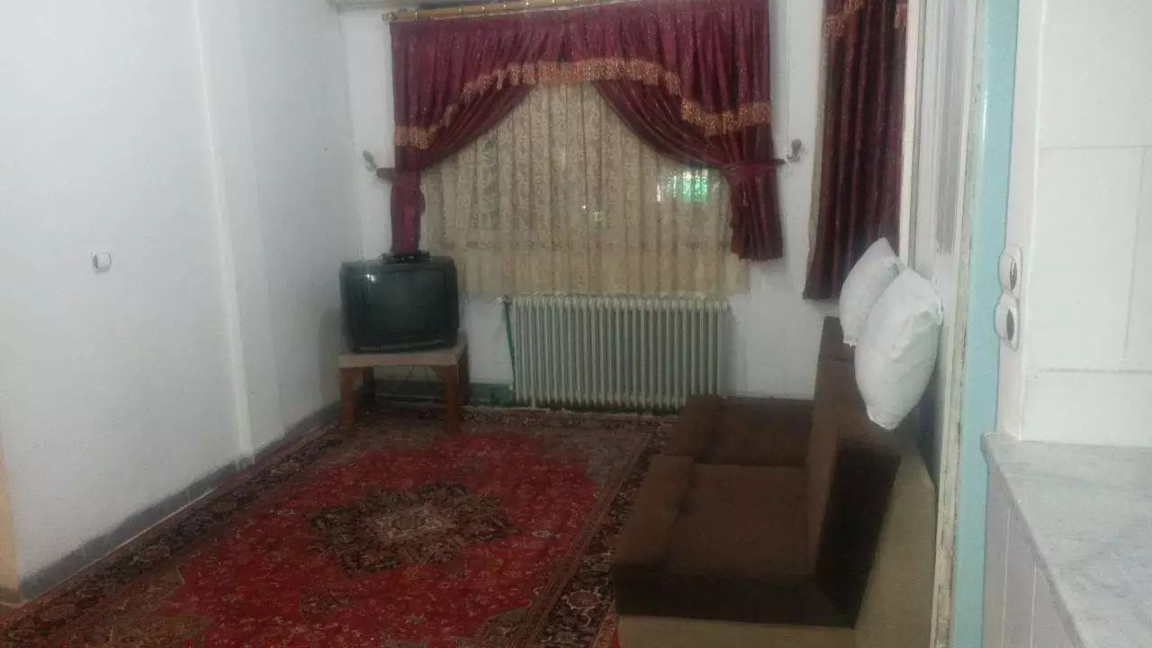 اتاق نشیمن هتل سامان با مبل، تلویزیون و فرش قرمز