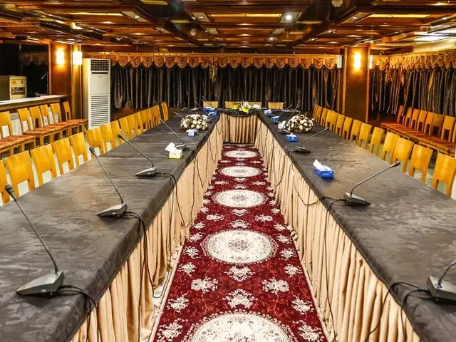 میزهای مستطیلی چیدمان‌شده در سالن کنفرانس جهانگردی دلوار