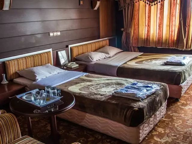 اتاق دو تخت با روتختی قهوه‌ای در جهانگردی دلوار