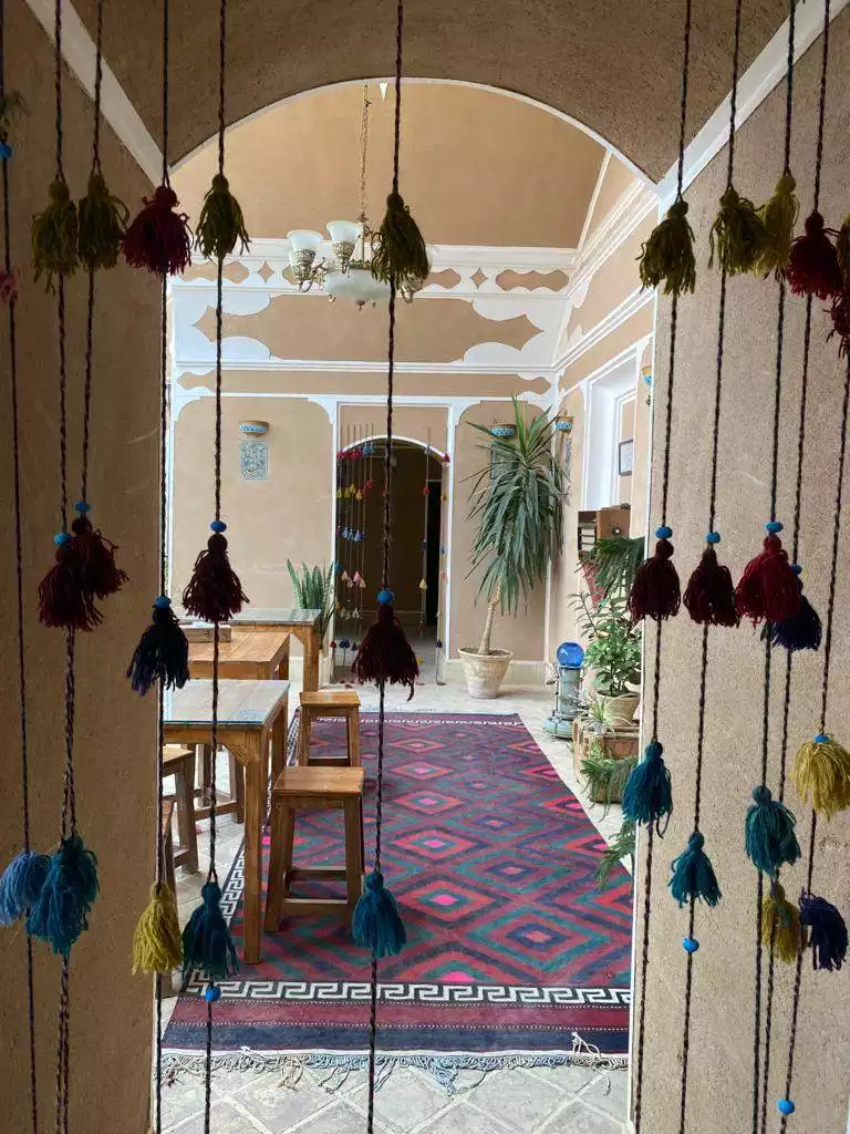 راهروی سنتی سرای کهن با فرش و آویزهای رنگی