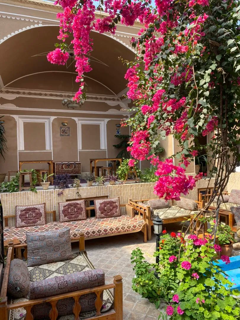 حیاط سرای کهن با گل‌های کاغذی و مبلمان سنتی