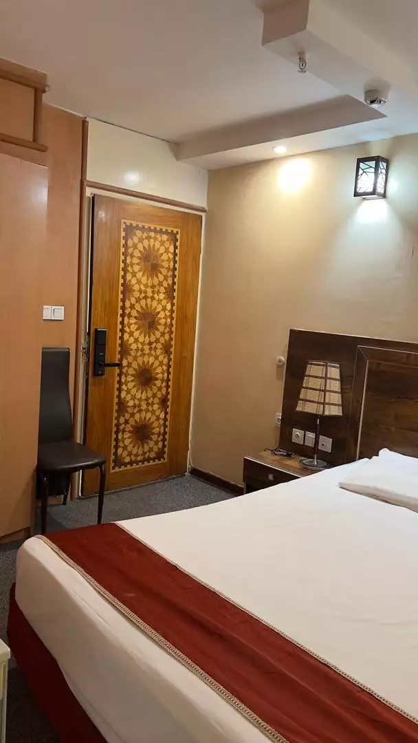تخت اتاق و در چوبی منبت‌کاری‌شده هتل بستان