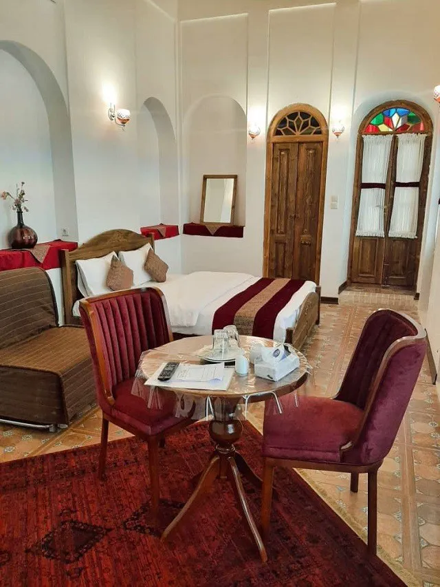 اتاق هتل اسفنجان با تخت و مبلمان زرشکی