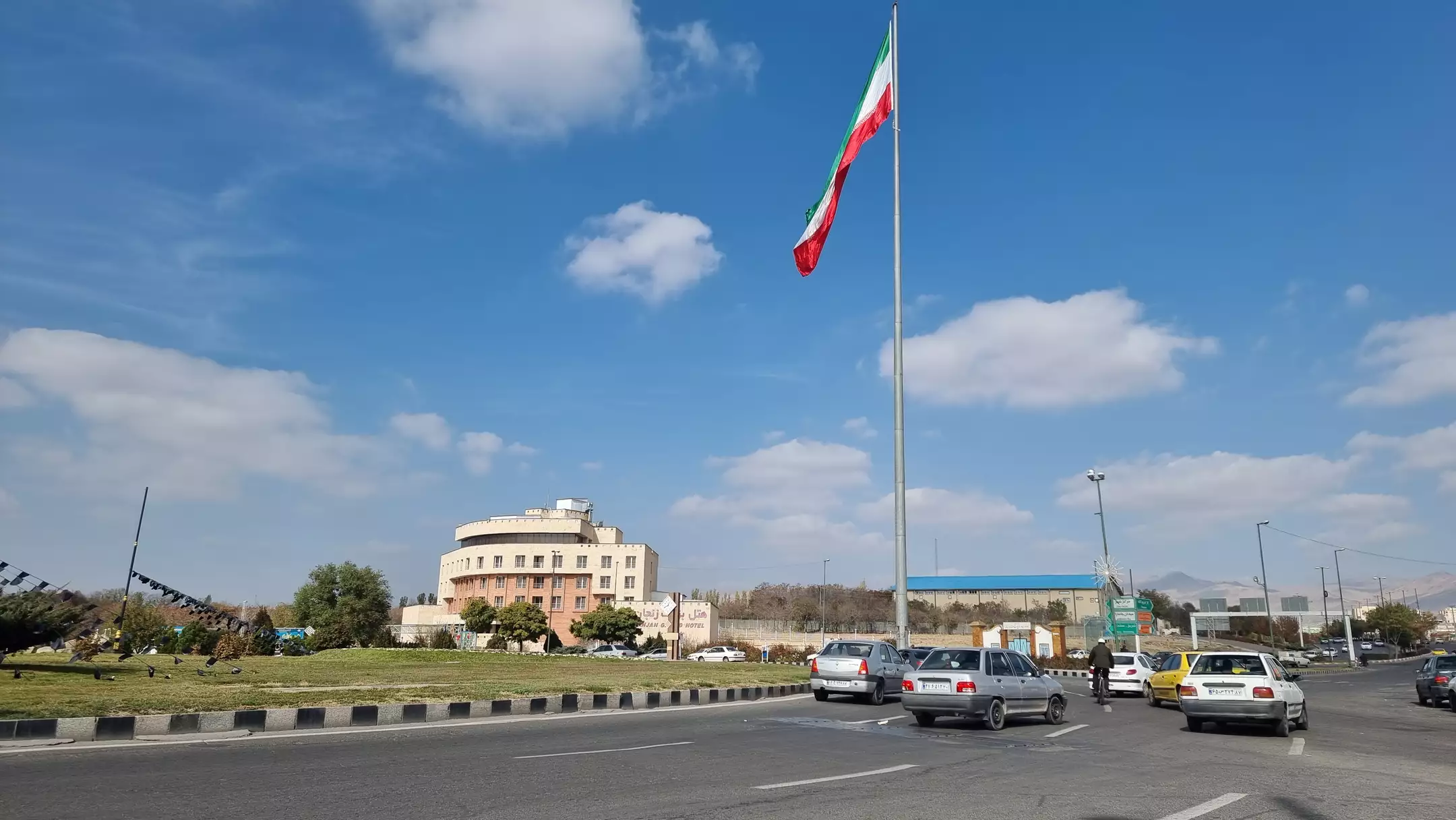 نمای هتل بزرگ کنار میدان و پرچم ایران