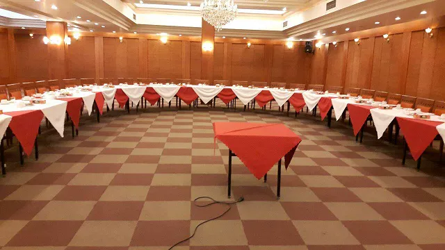 سالن پذیرایی بزرگ با میزهای U شکل و رومیزی قرمز