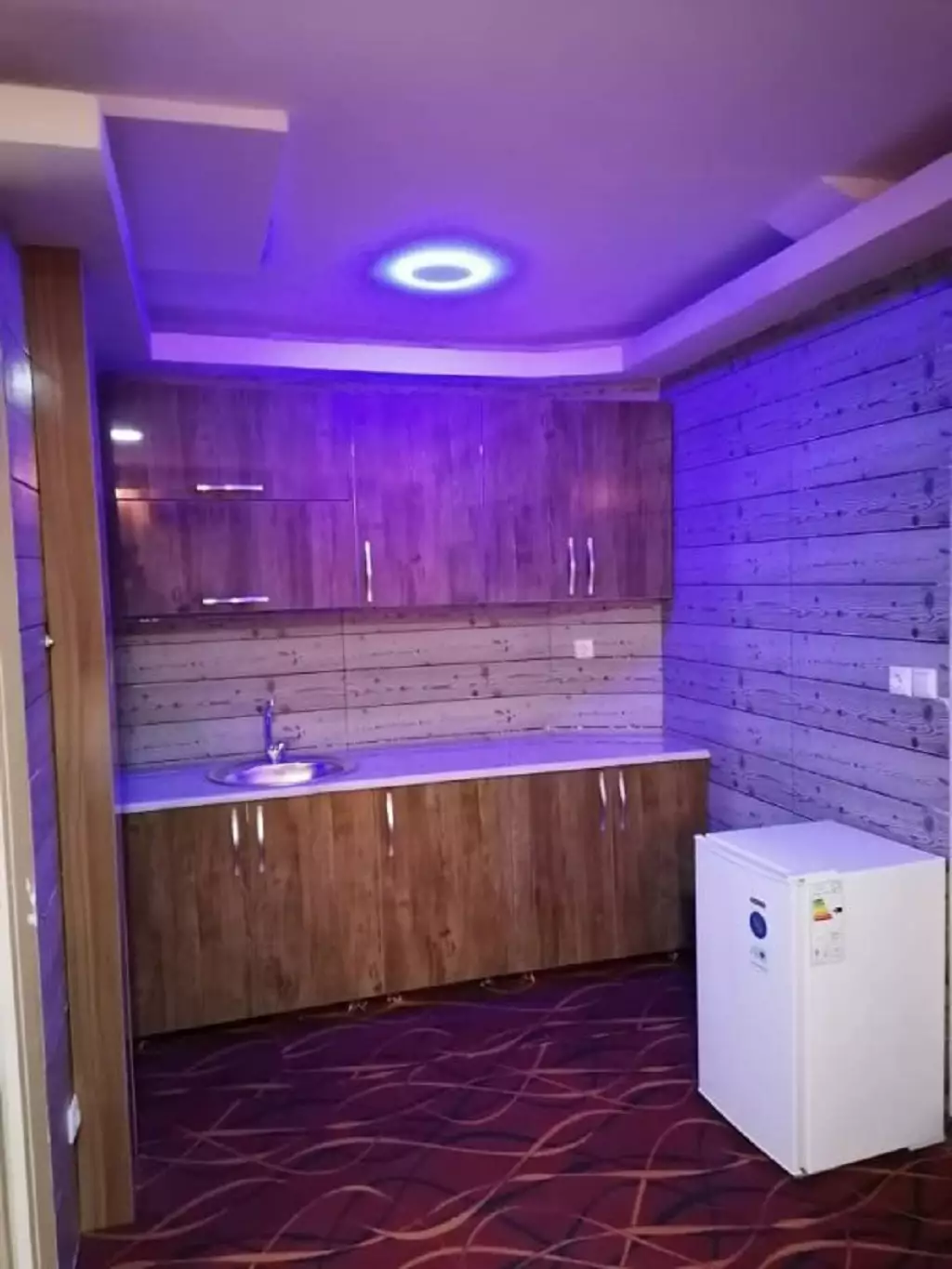 آشپزخانه هتل پویا با کابینت چوبی و یخچال