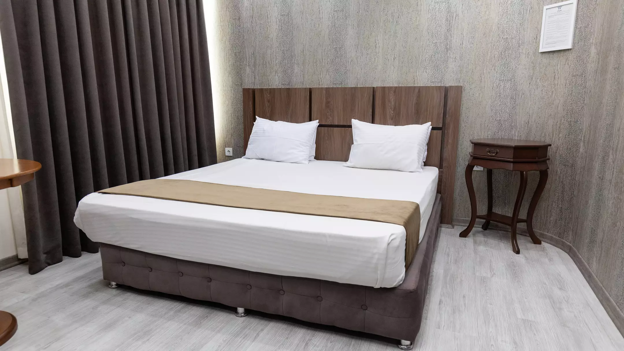 تخت دونفره اتاق هتل کارا با پرده‌های تیره