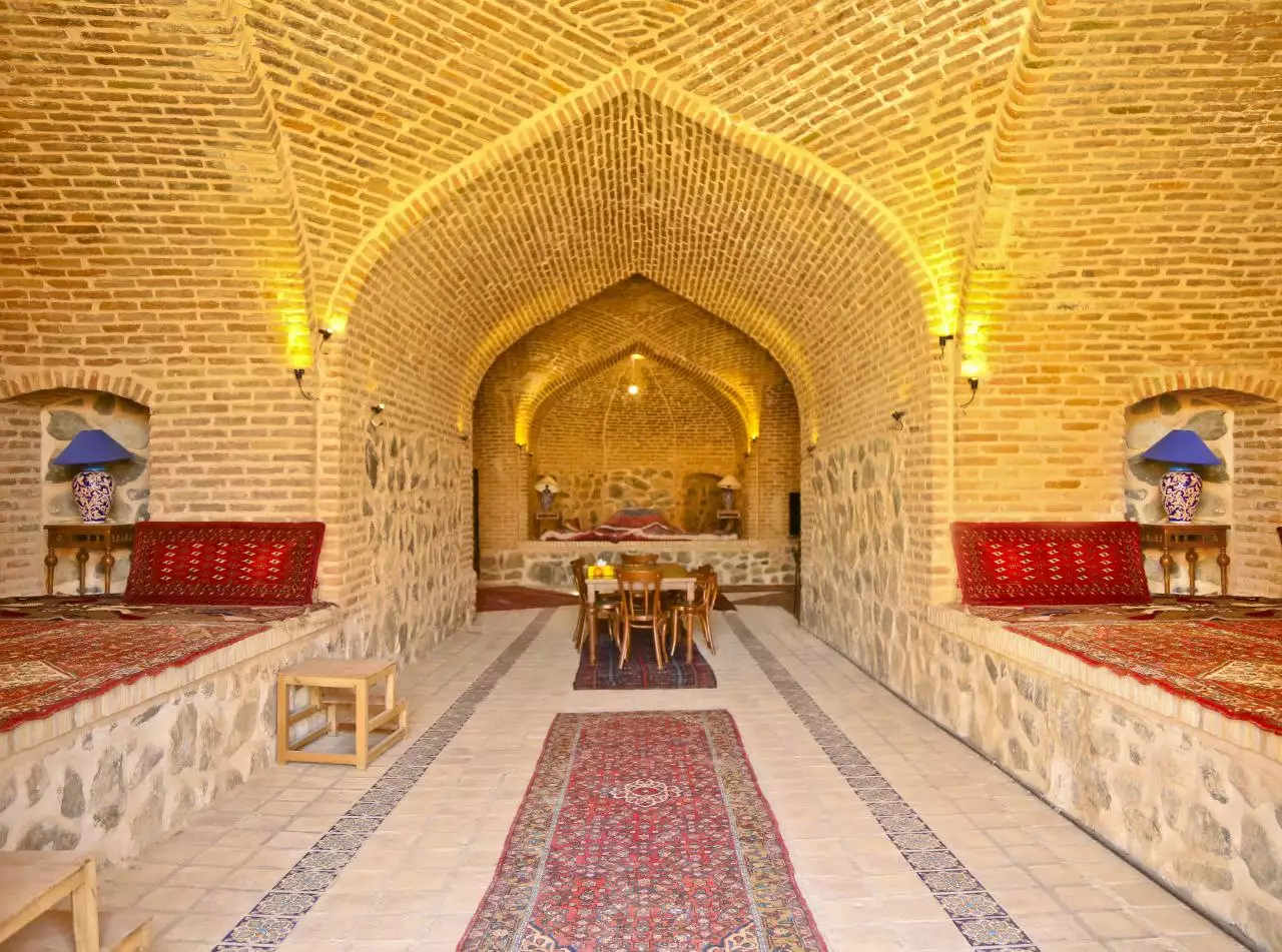 سالن آجری با فرش و تخت‌های سنتی هتل کوهاب