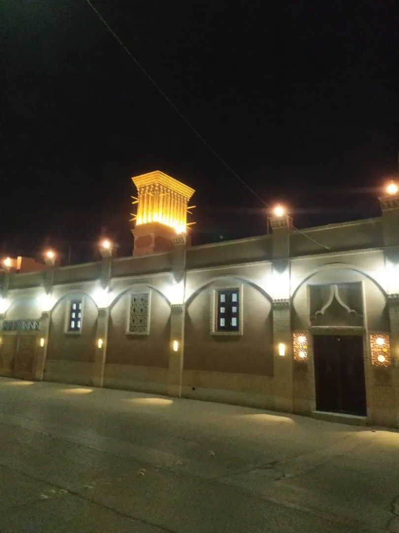 نمای شبانه دیوار آجری و برج روشن کوچه حنا