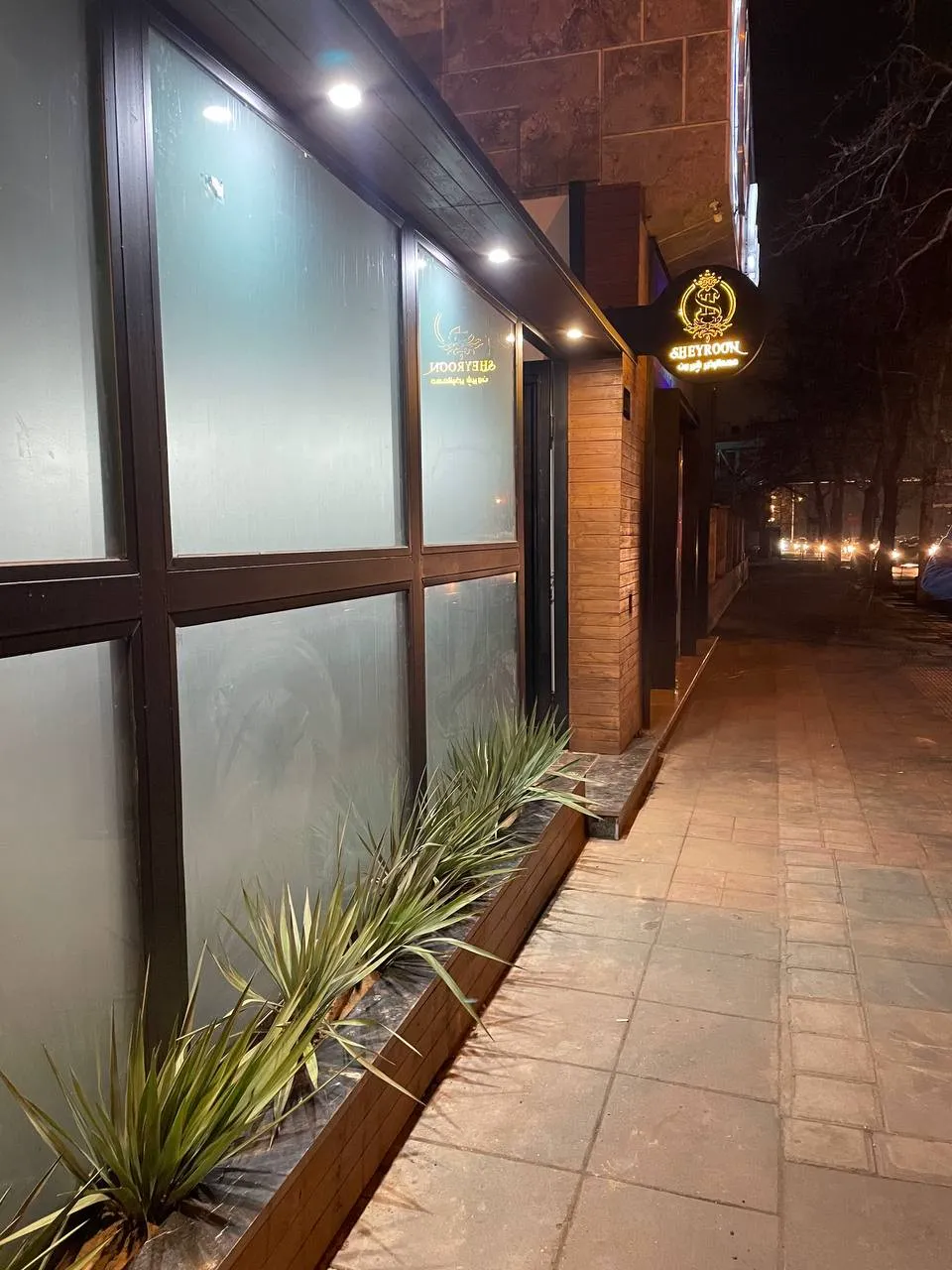 نمای ورودی شبانه هتل شیرون و باغچه کنار پیاده‌رو