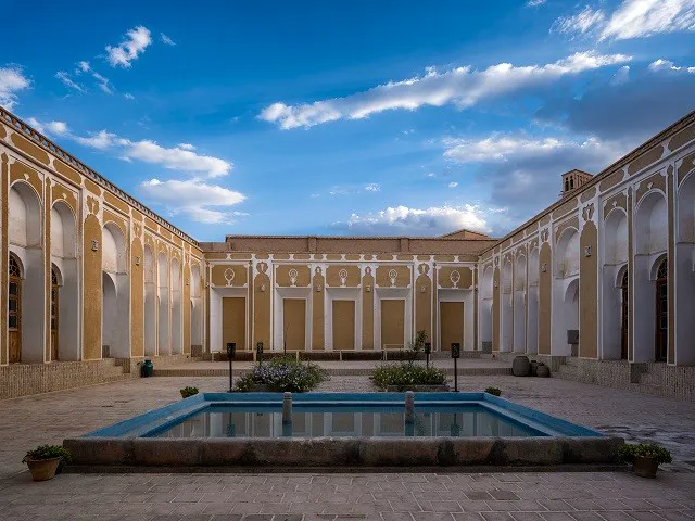 حیاط عمارت قجری با حوض مستطیلی و ایوان‌های قاجاری