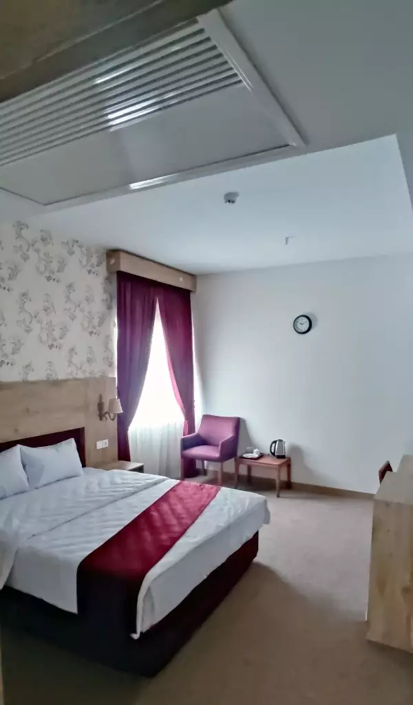 اتاق خواب هتل طبرستان با تخت دونفره و پرده زرشکی