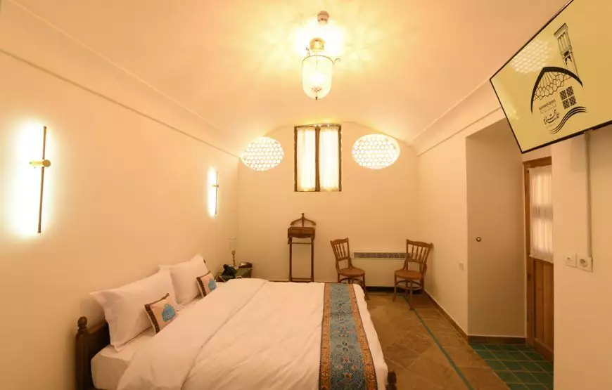 اتاق عمارت محمودیه با تخت دونفره و پنجره‌های مشبک