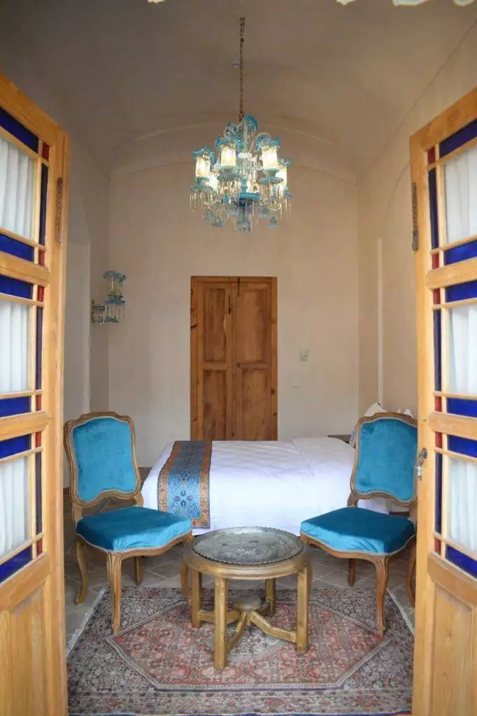 اتاق عمارت محمودیه با تخت، صندلی‌های آبی و لوستر