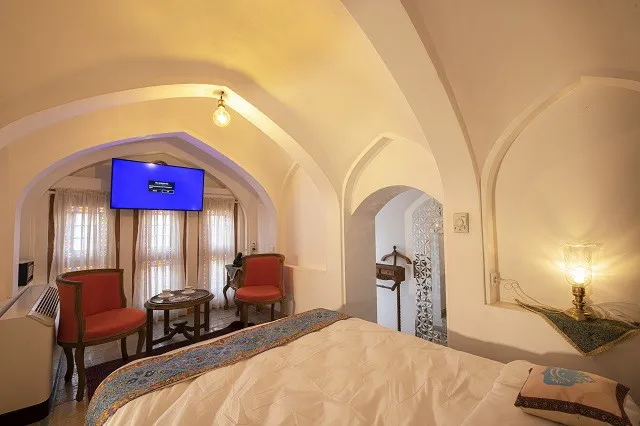 اتاق عمارت محمودیه با تخت، صندلی‌های قرمز و تلویزیون