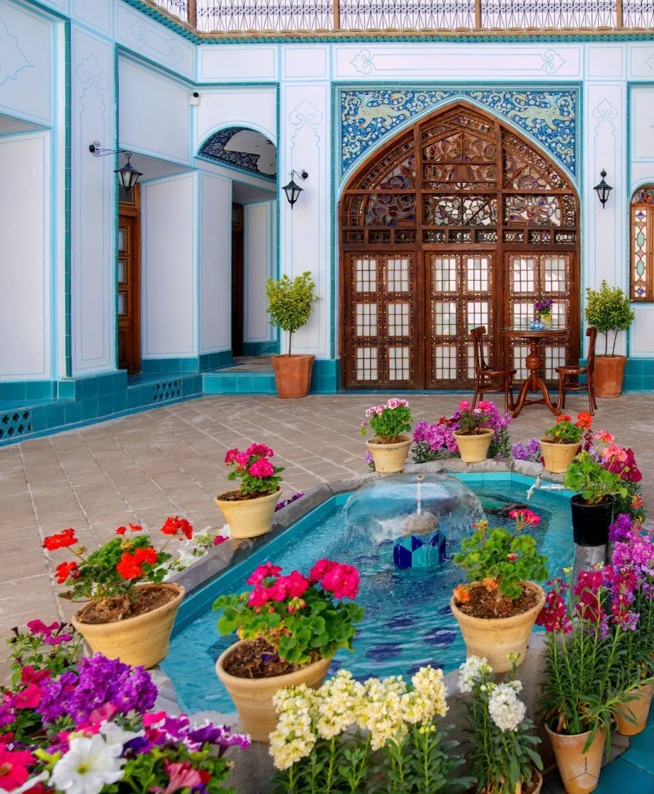 حیاط هتل شیخ لطف الله با حوض و گلهای رنگارنگ