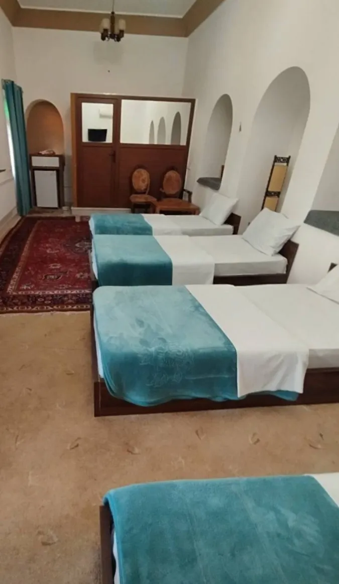 چند تخت یکنفره با روتختی فیروزهای در خانه ترنج