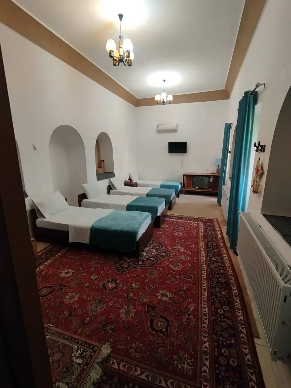 اتاق سهتخته خانه ترنج با روتختی فیروزهای و فرش