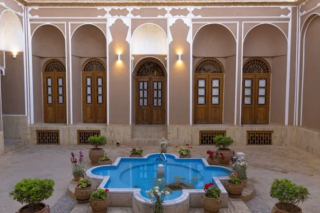 حیاط سنتی کتروا با حوض آبی و گلدان‌ها