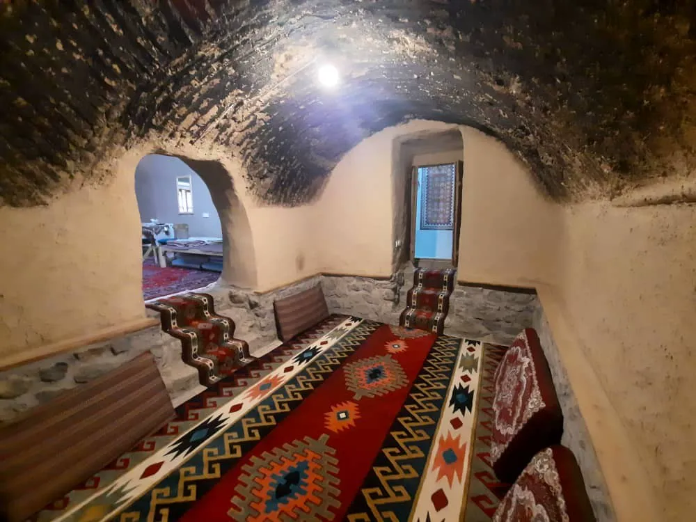 نشیمن سنتی اقامتگاه افوشتا با فرش و سقف آجری طاقی