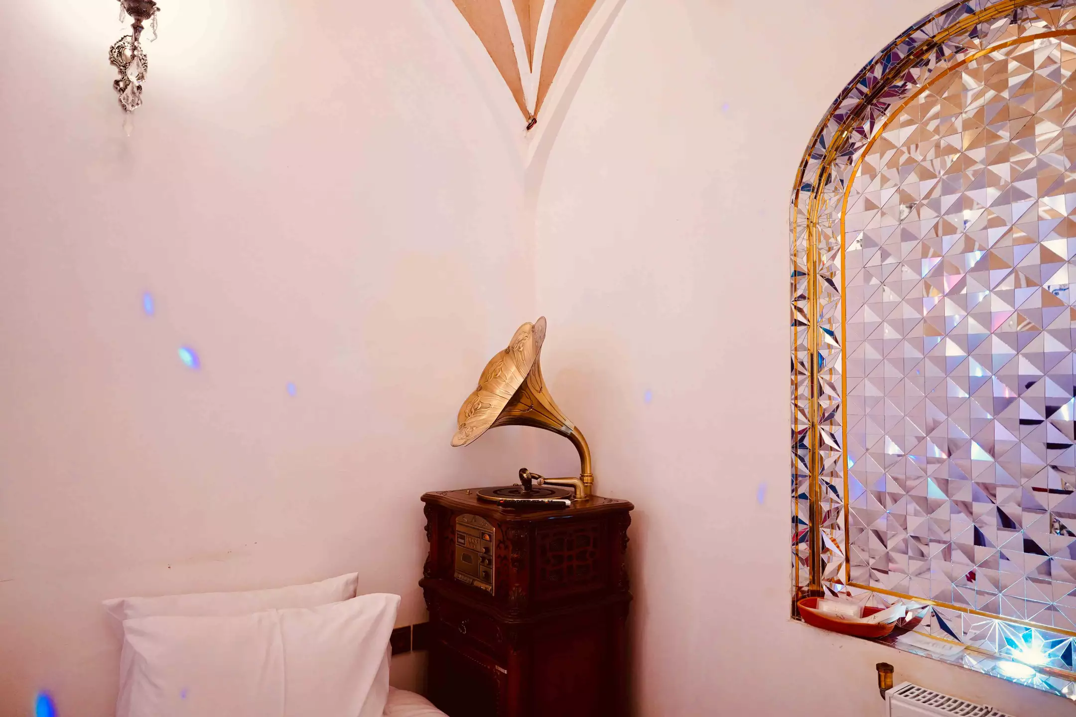 گرامافون قدیمی کنار تخت و پنجره مشبک هتل شیخداد
