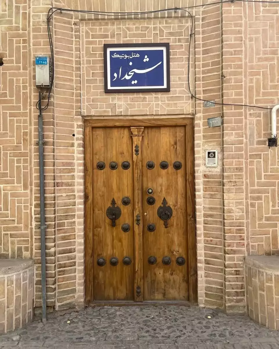 در ورودی چوبی هتل شیخداد با کوبه‌های فلزی