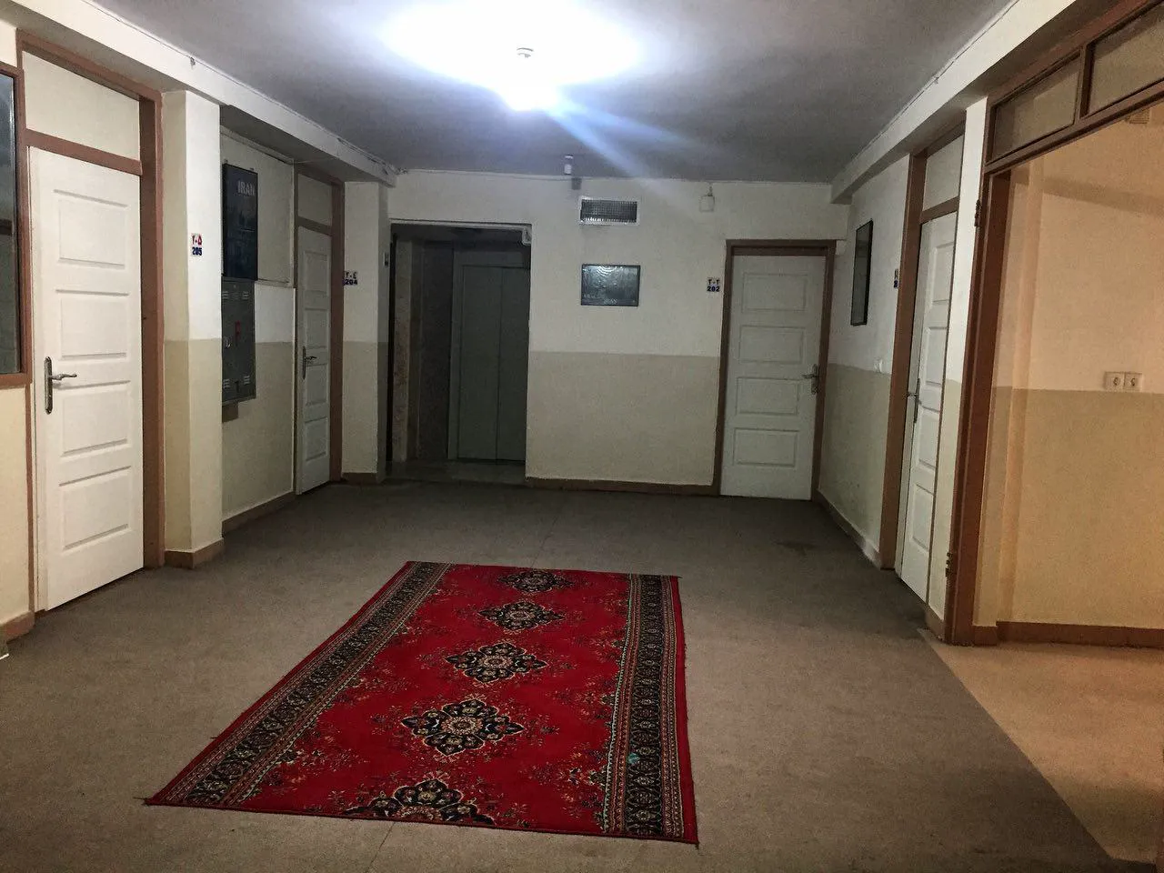 راهروی هتل راه کربلا با فرش قرمز و درهای اتاق