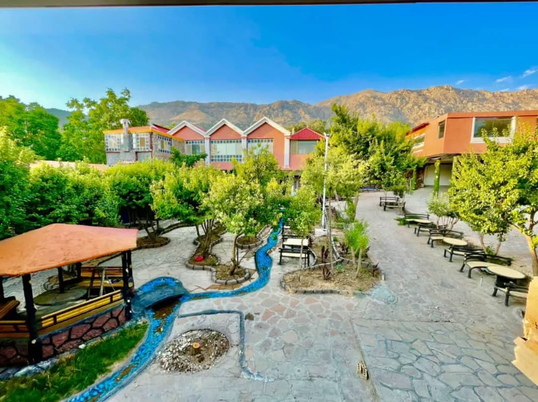 محوطه سرسبز هتل حوض دال زاگرس با جوی آب و کوهستان