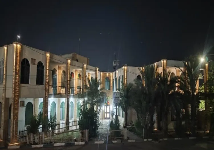 ساختمان هتل جهان آرا در شب با حیاط و نخل‌ها