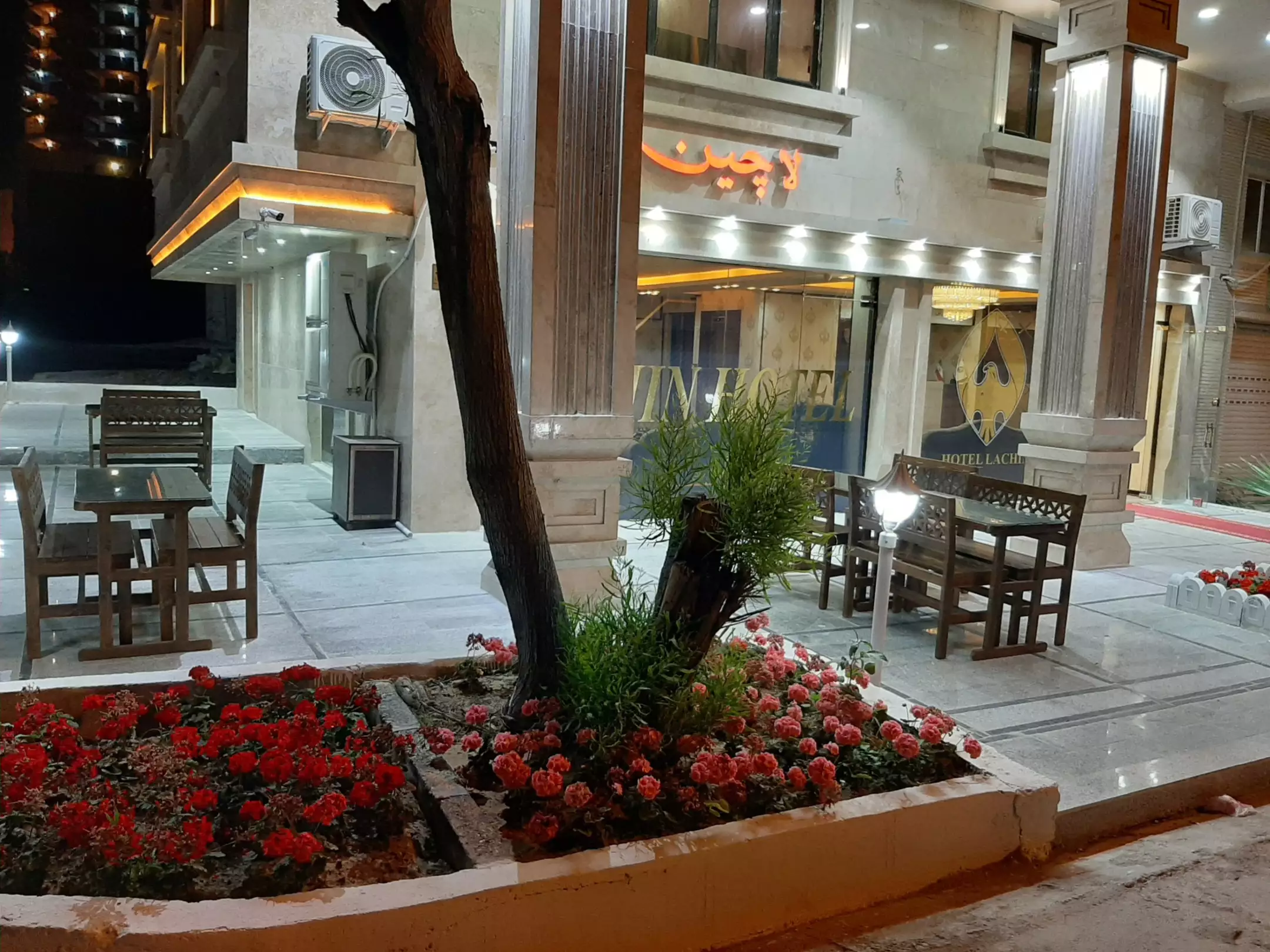 ورودی هتل لاچین با باغچه گل و میزهای بیرونی