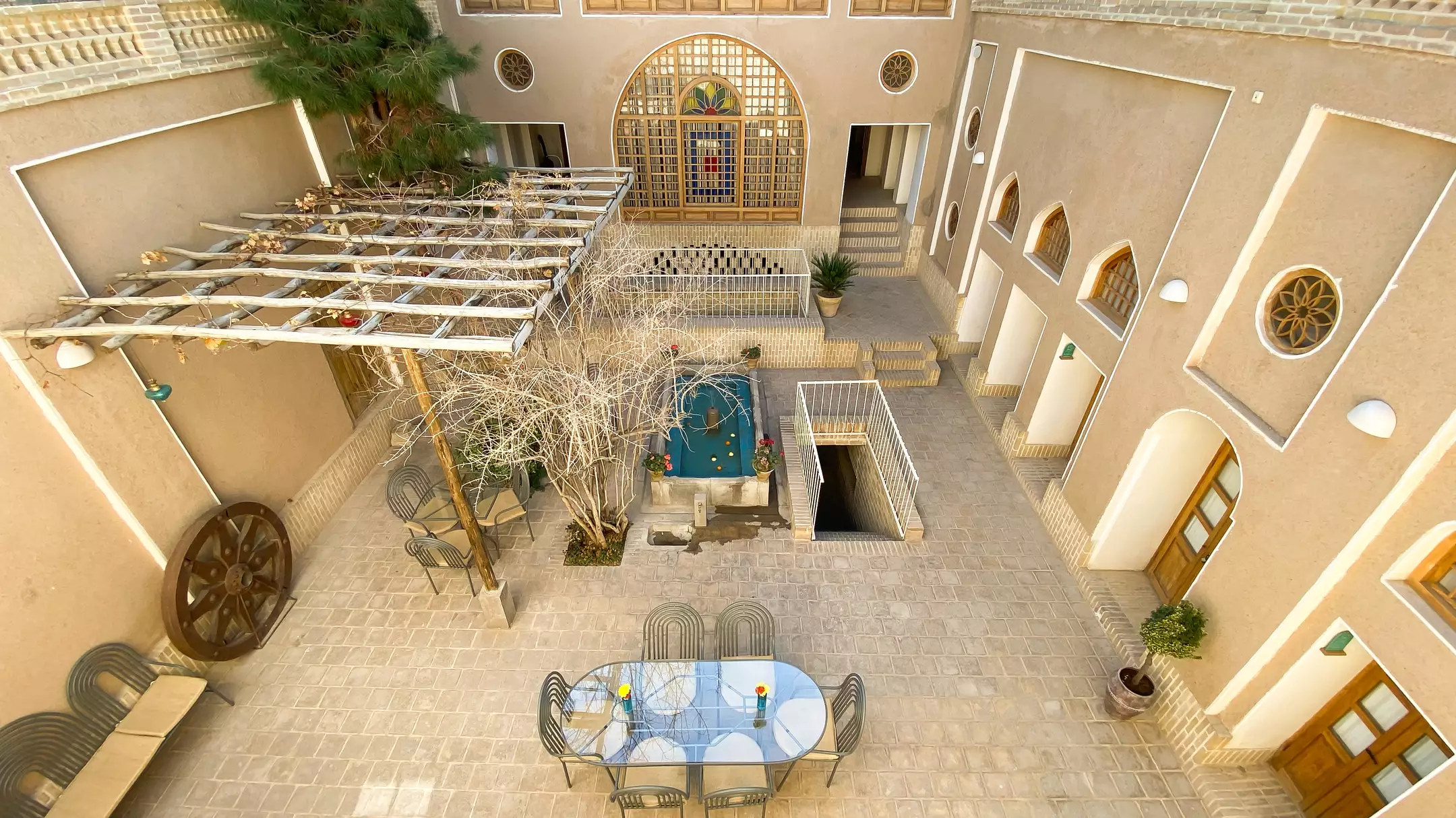 حیاط سنتی با حوض و میز در هتل دالان جهان