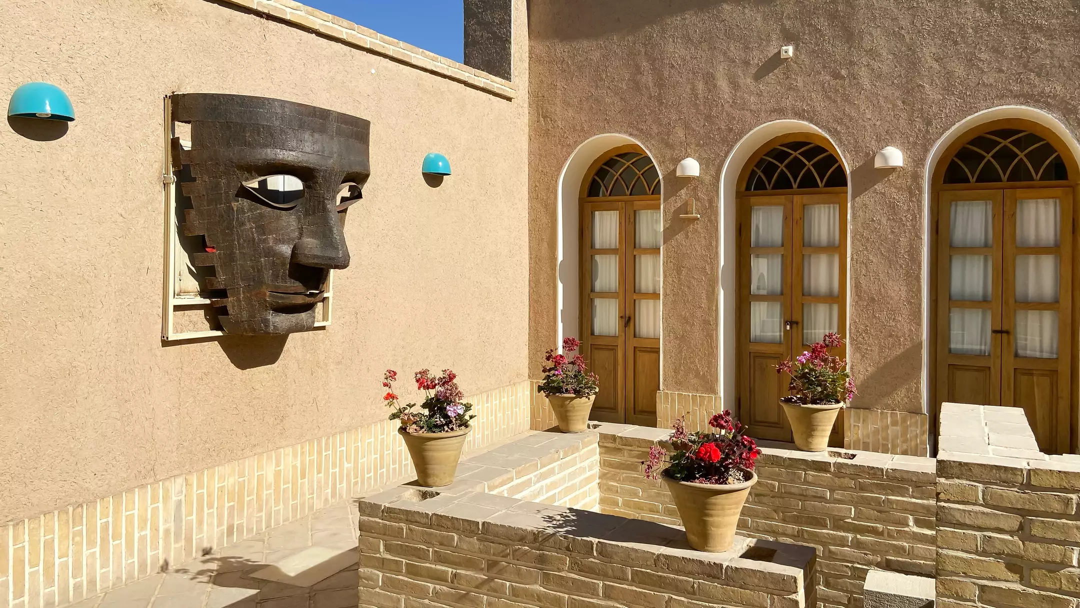 حیاط دالان جهان با پنجرههای قوسی و گلدان گل