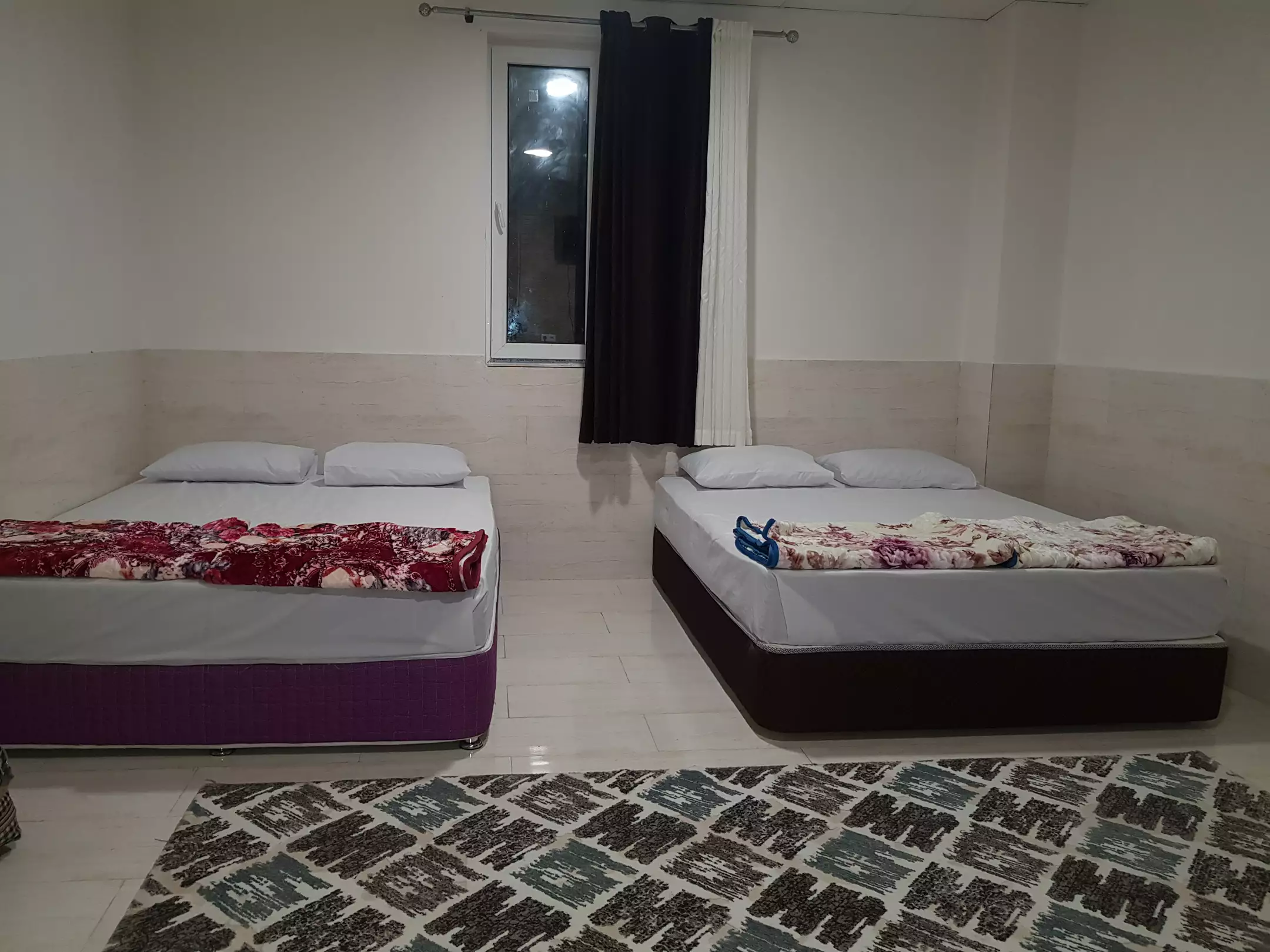 اتاق هتل گیلان با دو تخت و فرش طرح‌دار