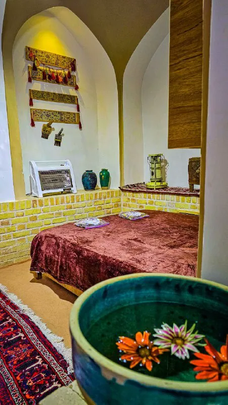 اتاق عمارت سرهنگ با تخت سنتی و حوضچه گل‌آرایی‌شده
