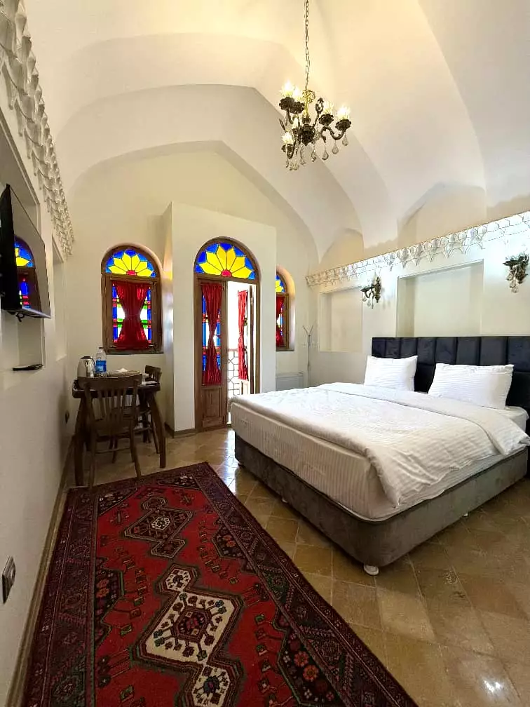 اتاق عمارت سهروردی با تخت دونفره و پنجره‌های رنگی