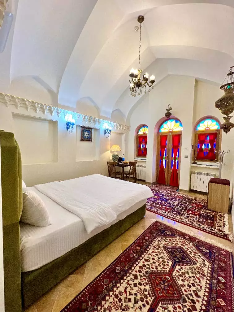 اتاق عمارت سهروردی با پنجره‌های رنگی و تخت دونفره