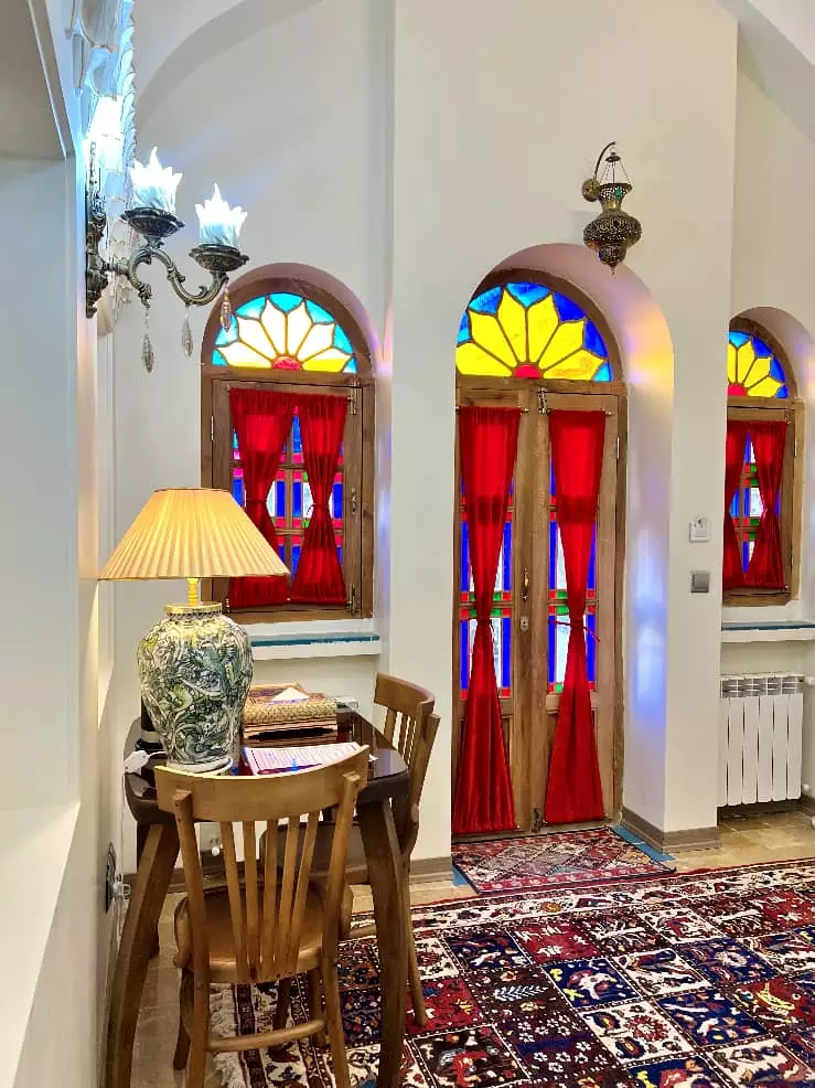 پنجرههای رنگی و میز چوبی در عمارت سهروردی